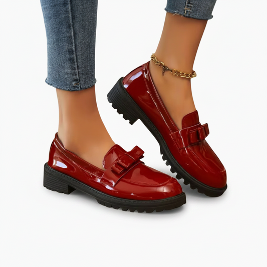 Gros plan sur le cuir verni et la texture lisse des mocassins rouges brillants, signe de leur qualité supérieure.