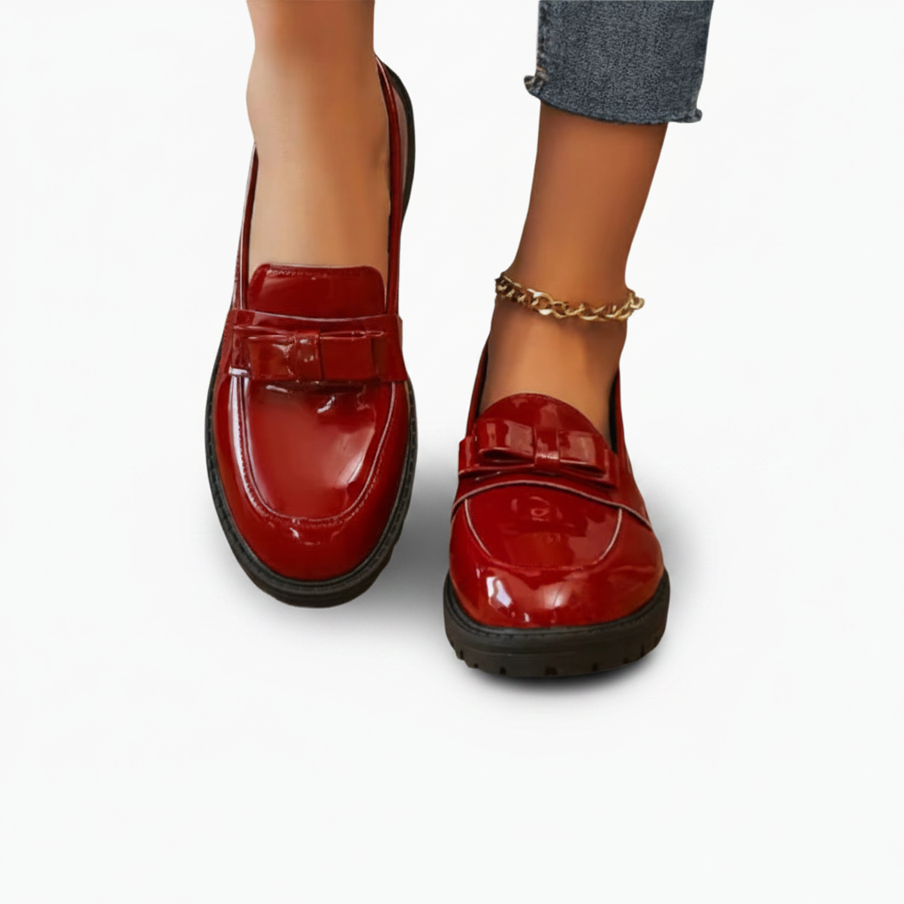 Mocassins rouges vifs portés avec un pantalon de tailleur noir, créant une allure professionnelle moderne et sophistiquée.
