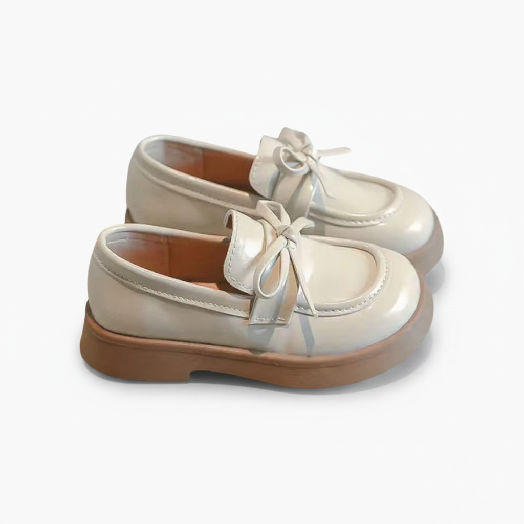 Détail de la couture fine et de la sangle classique du mocassin beige, gage de qualité pour enfant.