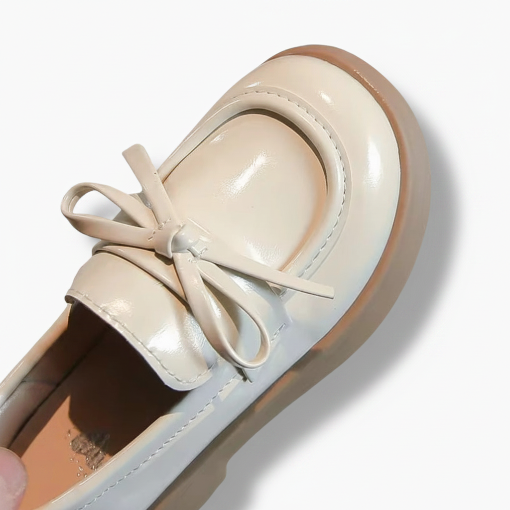 Petits pieds chaussés du mocassin vernis beige, marchant avec grâce et assurance sur un chemin.