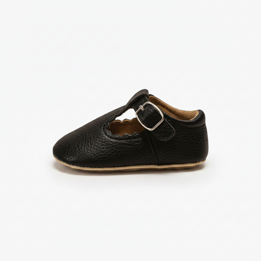 Profil latéral des mocassins bébé noirs, mettant en avant leur souplesse et design intemporel.